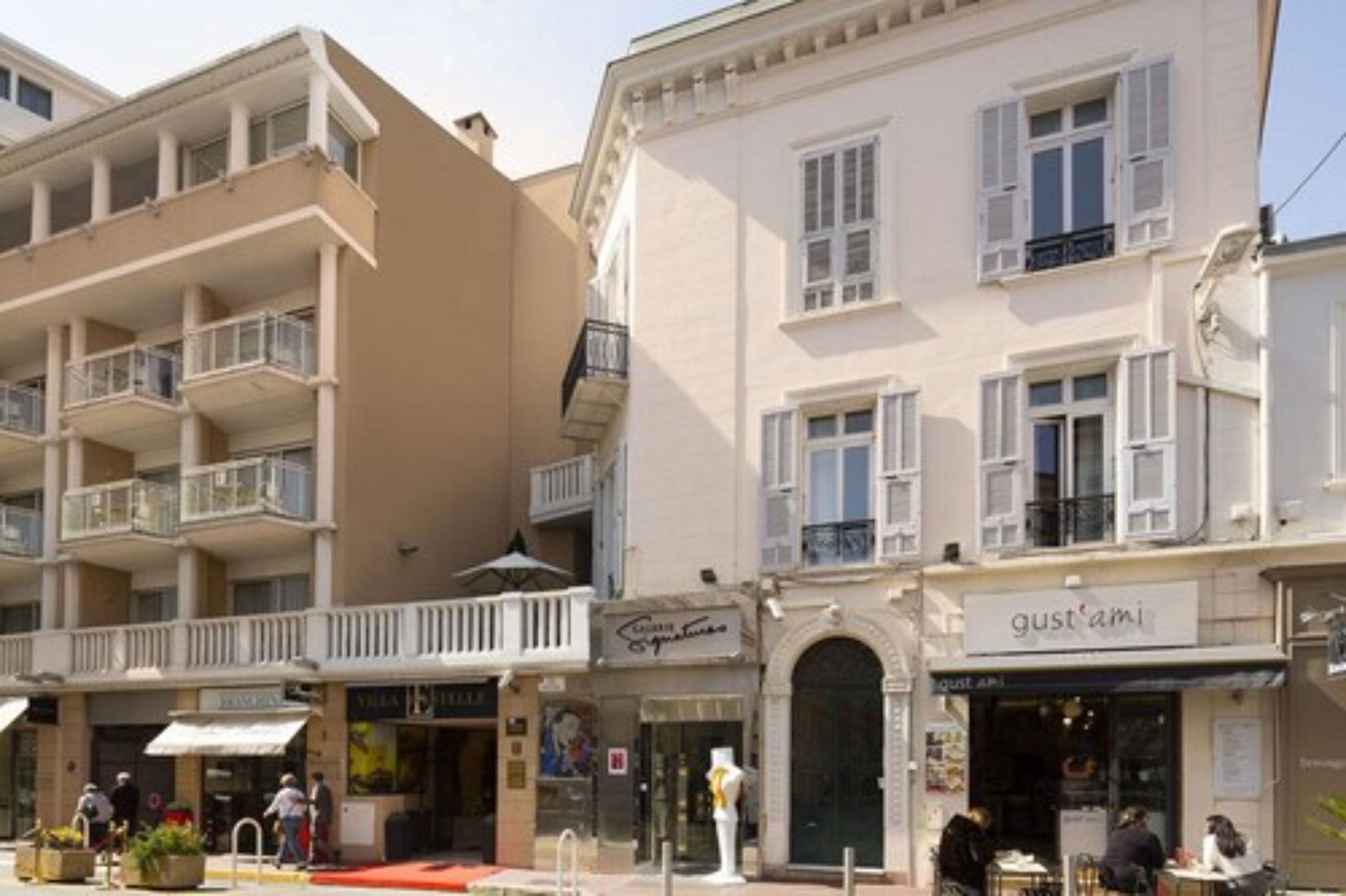 A multi-story building with balconies, storefronts, and a café.