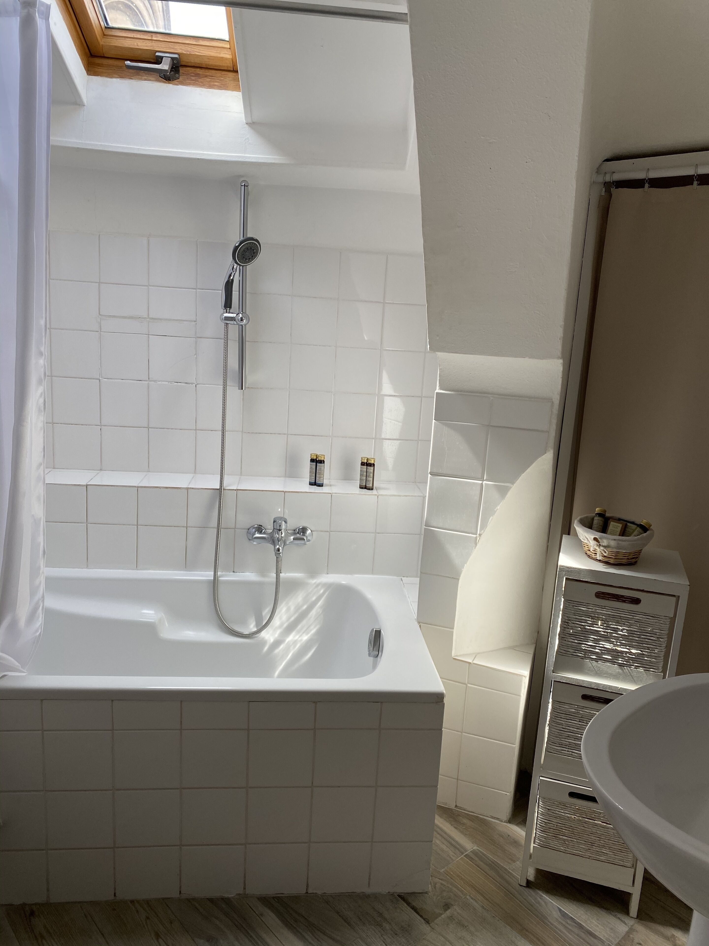 Une salle de bain moderne avec une baignoire sur pieds, une douche et une lucarne au plafond.