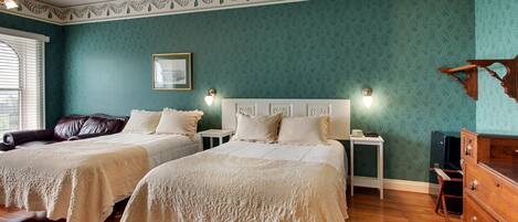 A room with two beds, a wooden dresser, a nightstand, and a framed picture on the wall.