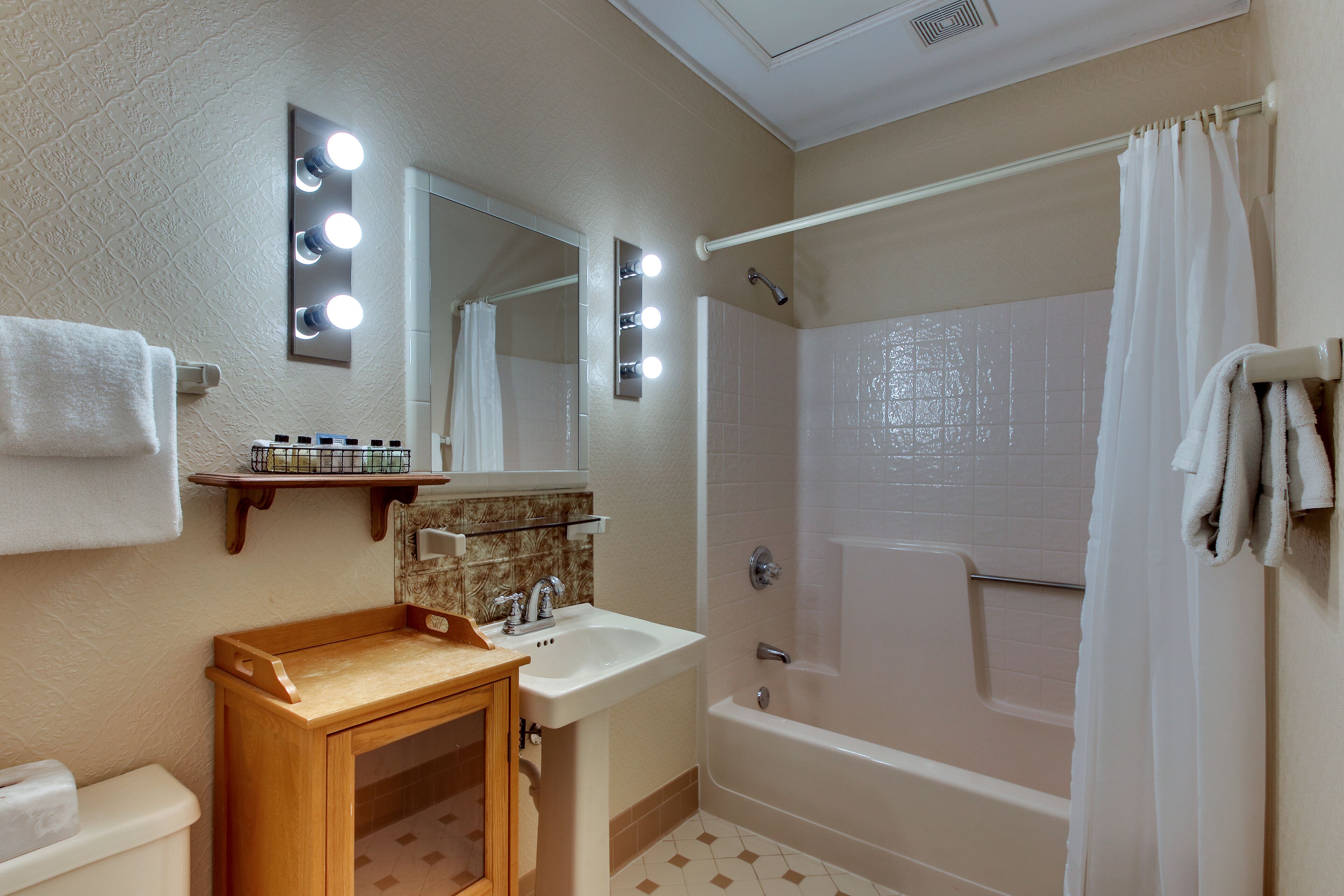 A bathroom with a sink, mirror, vanity, and a bathtub.