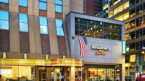 Ett Marriott Residence Inn-hotell med en framträdande amerikansk flagga, stora fönster och en väl upplyst entré.