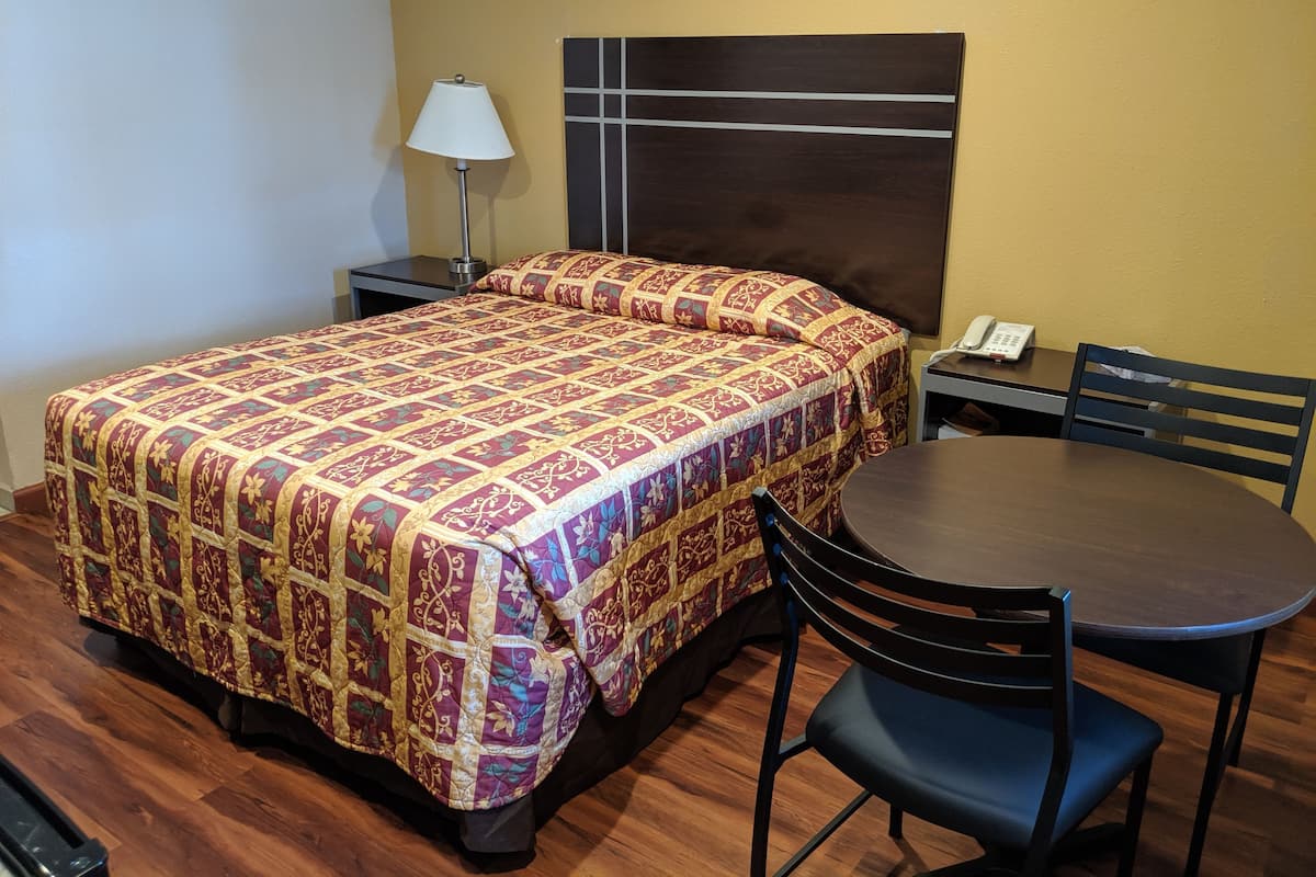 A hotel room with a bed, a desk with a telephone, a chair, and a table.