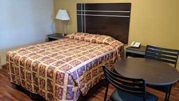 Una habitación de hotel con una cama, un escritorio con teléfono, una silla y una mesa.