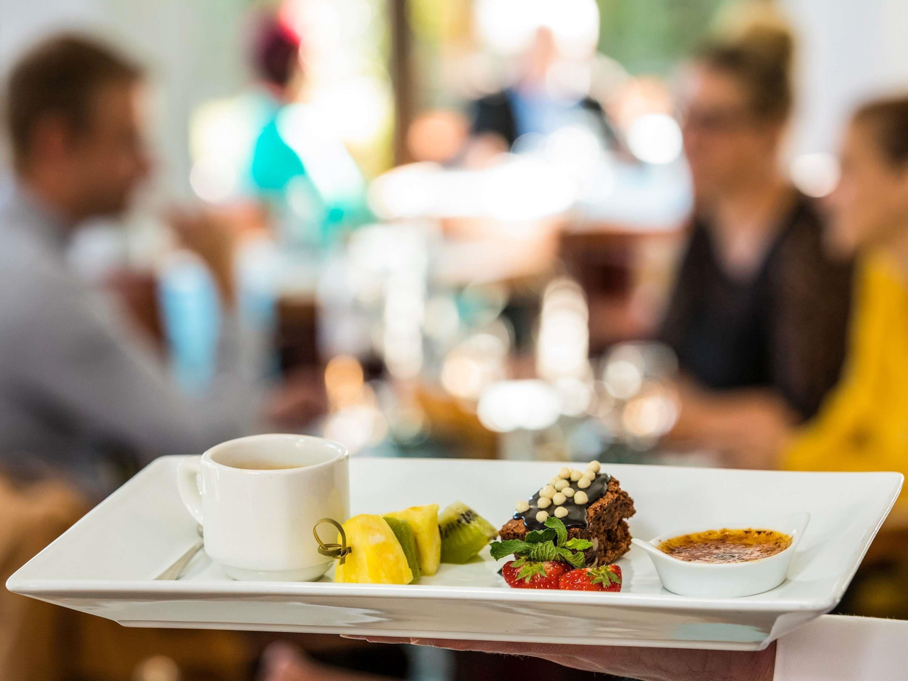 Una bandeja con una taza, fruta, postre y salsa.