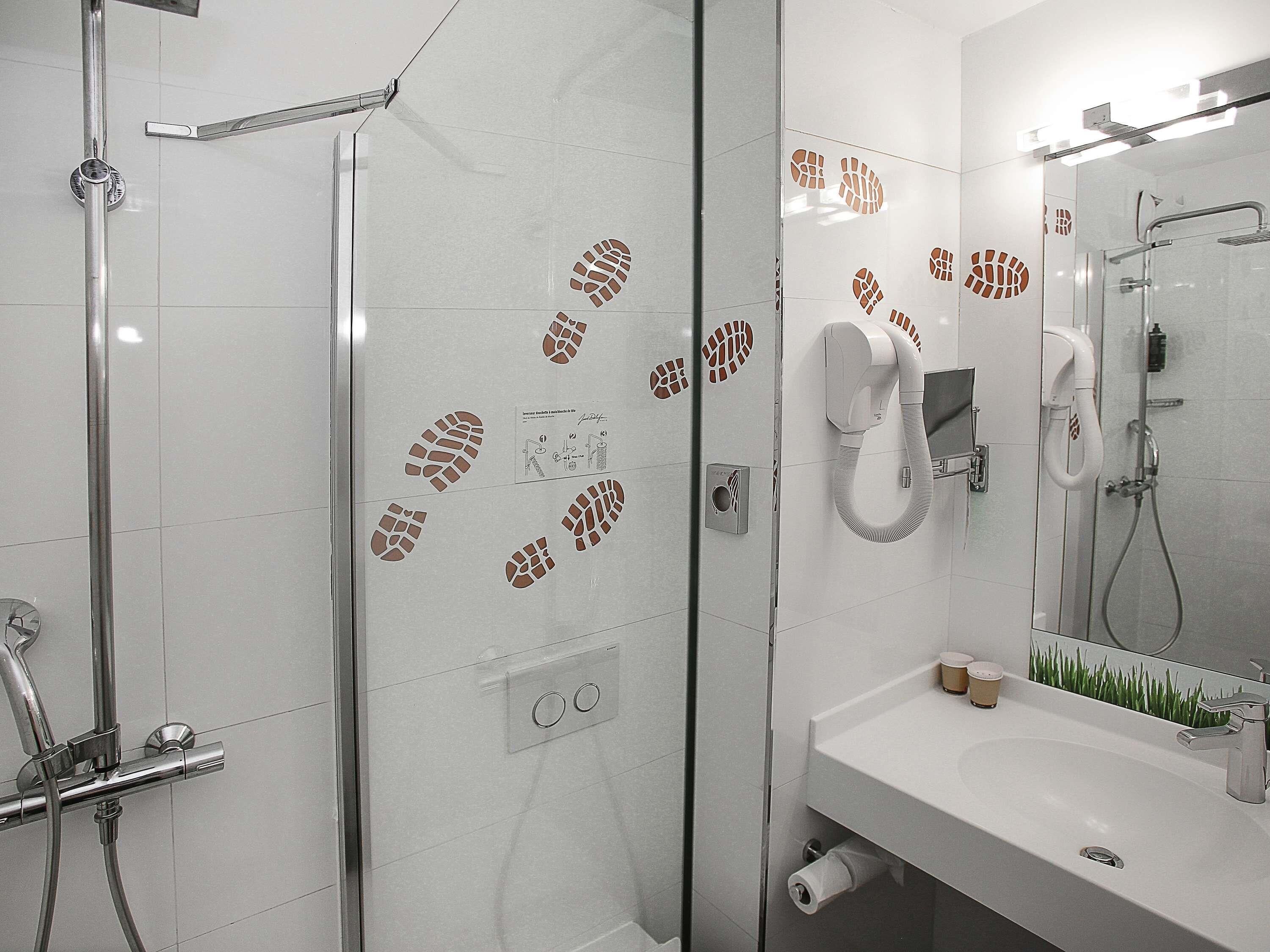Une salle de bain moderne avec une douche à parois de verre, un lavabo blanc avec un miroir et un porte-serviettes.