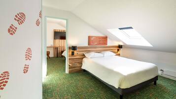 A hotel room with a bed, a desk, and a chair. There is a skylight above the bed.
