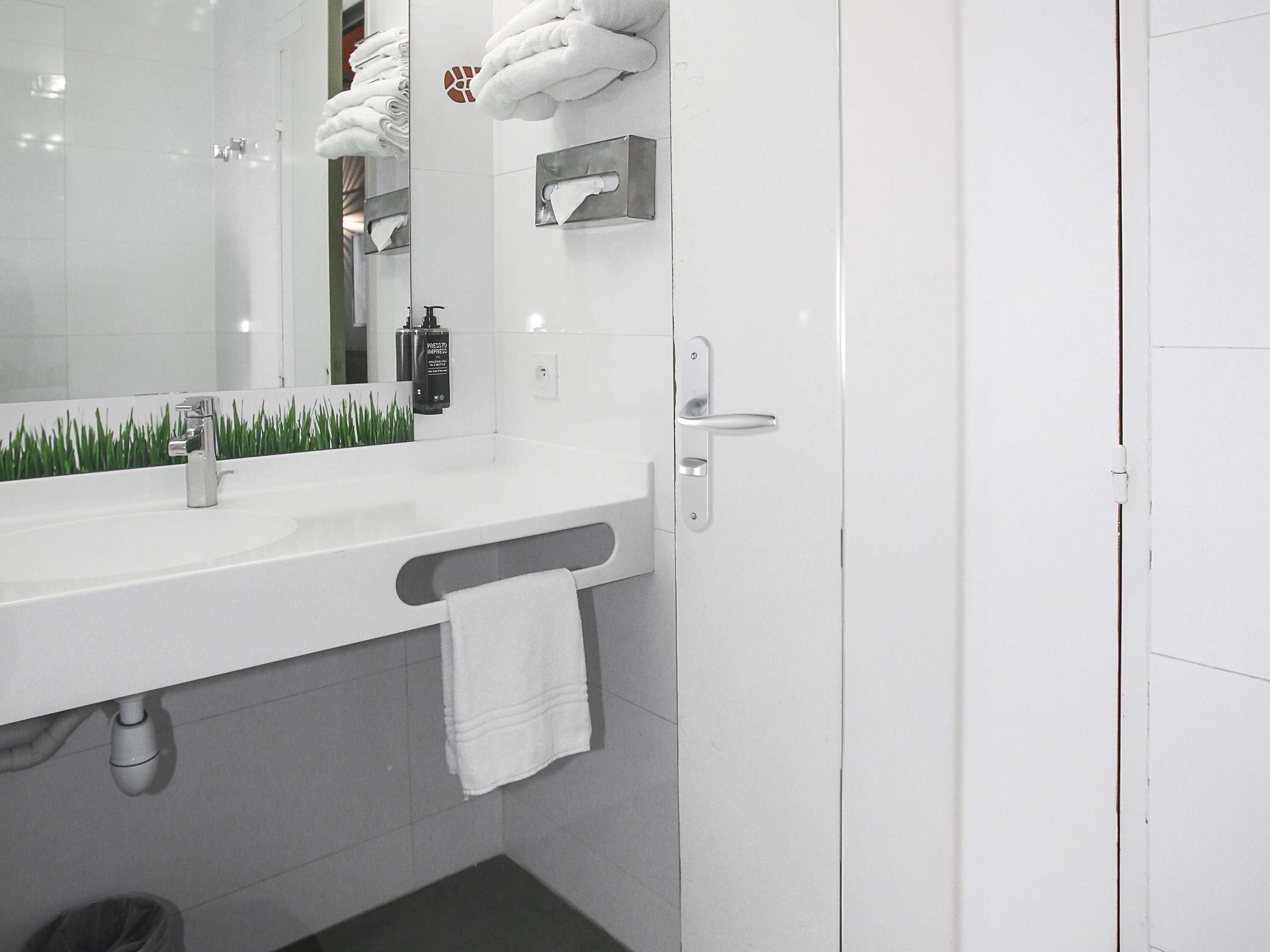 A modern bathroom with a white sink, a towel rack, a mirror, and a towel hanging on the wall.