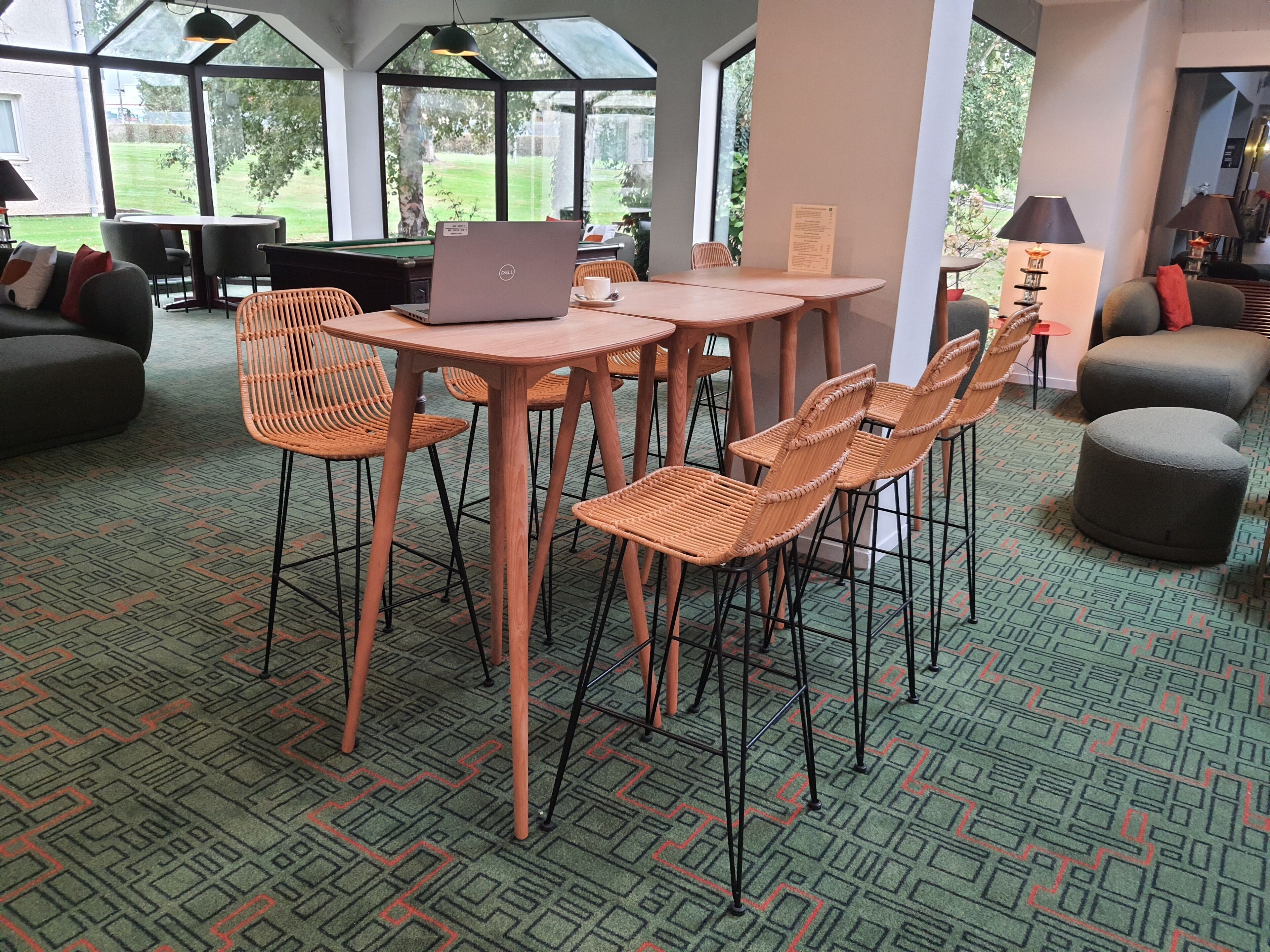 Un espacio interior amplio con mesa de billar, una computadora portátil sobre una mesa y varias sillas de mimbre.