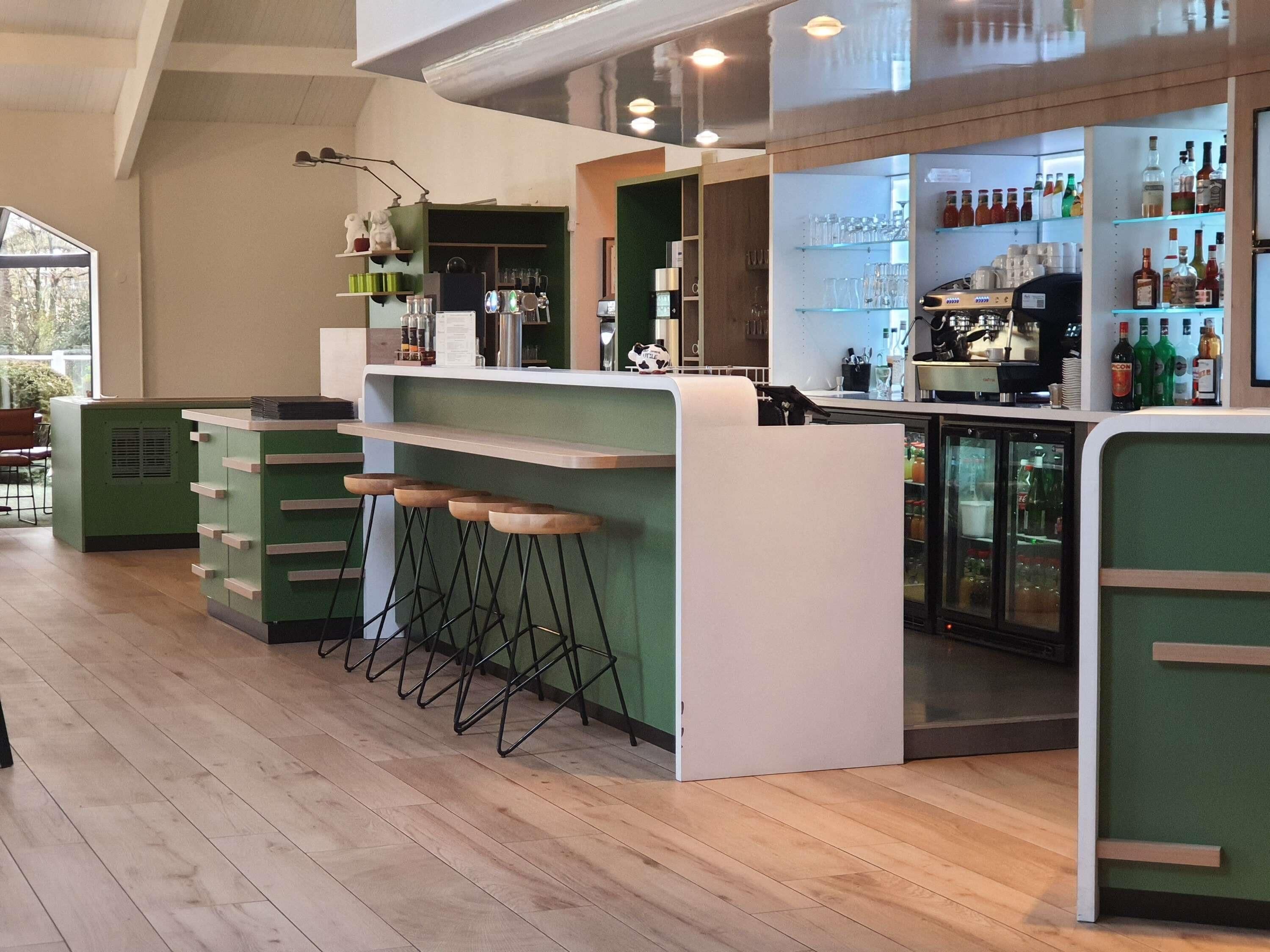 Una zona de bar con taburetes, estanterías llenas de botellas y un refrigerador.