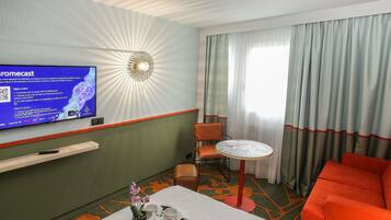 Une chambre d’hôtel équipée d’une télévision diffusant un service de streaming, d’un lit avec un plateau de petit-déjeuner, d’une petite table et d’une chaise.