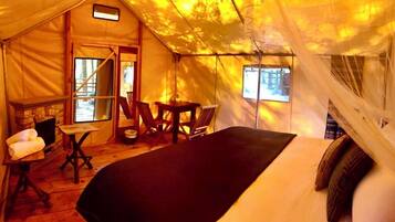 A tent-style room with a bed, a table, chairs, and a fireplace.