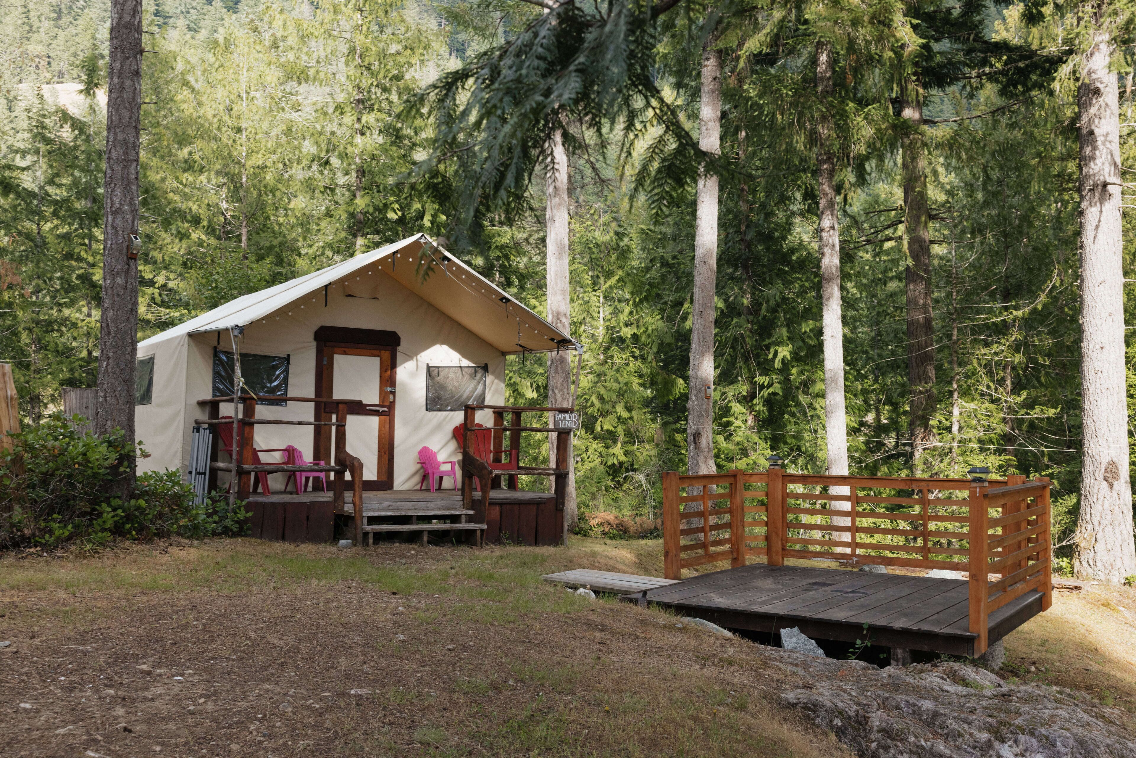 A small cabin with a porch, surrounded by tall trees.