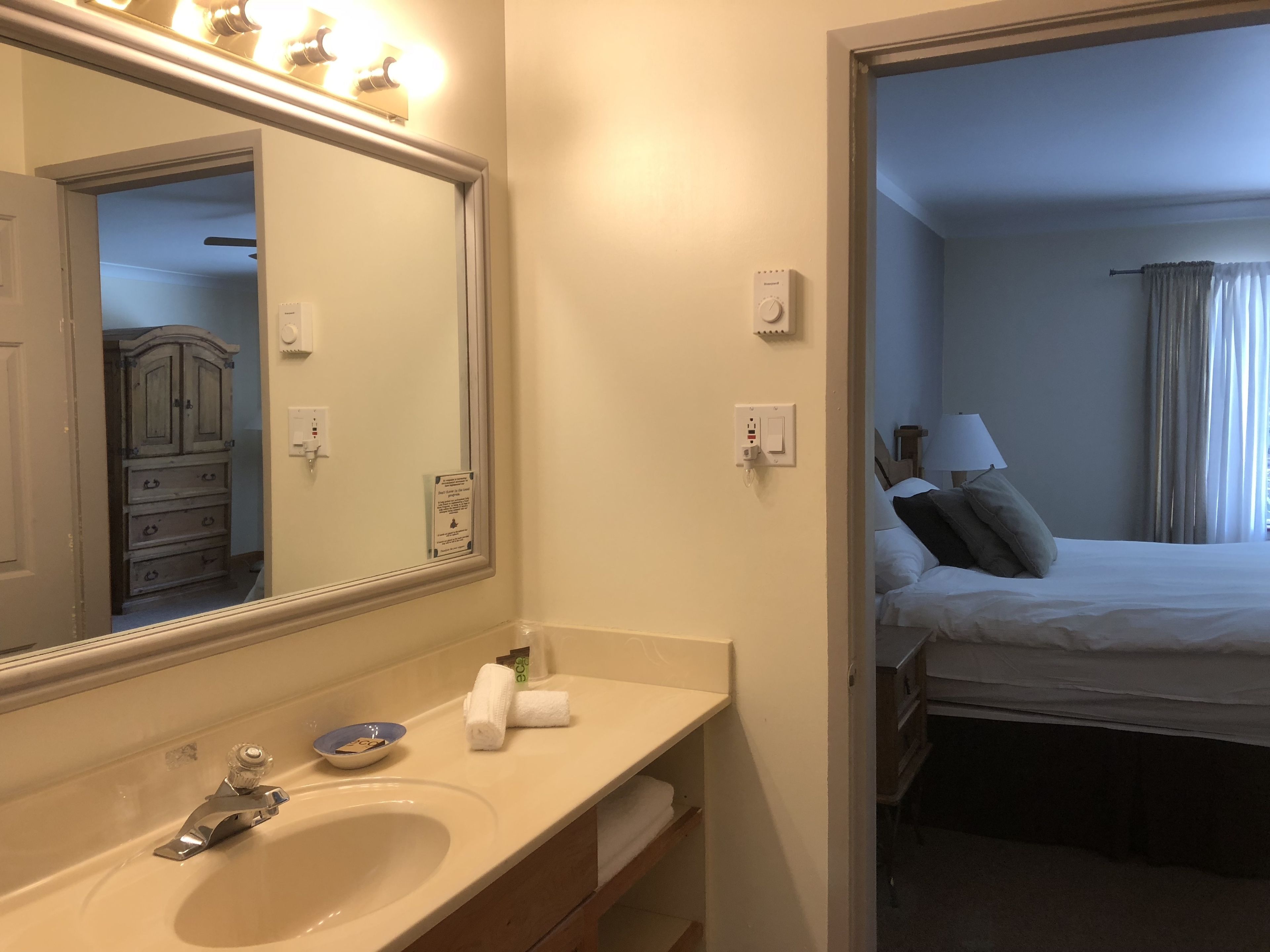 A hotel bathroom with a sink, mirror, and towel dispenser.