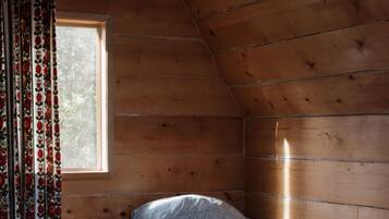Experience a cozy cabin retreat with a sloped ceiling, a comfortable bed, and a warm atmosphere.