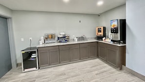 Una cocina moderna con encimeras de granito, armarios empotrados, cafetera, dispensador de zumo y microondas.