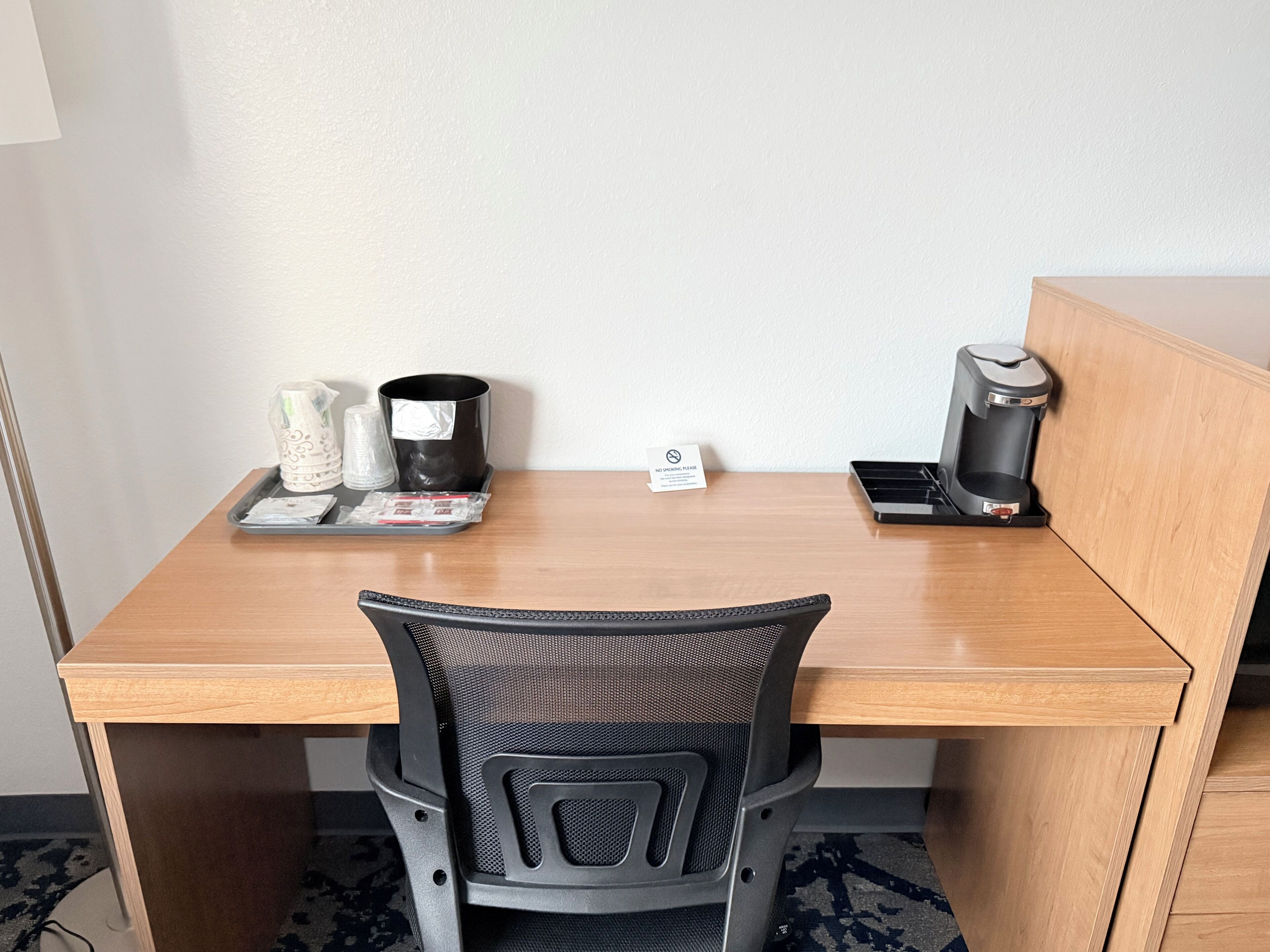 Un bureau en bois avec deux machines à café, une poubelle et un panneau indiquant «Il est interdit de fumer».