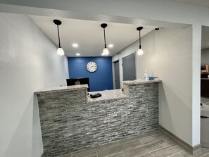 A reception area with a stone counter, a clock, and a desk with a computer.