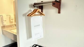 A bathroom with a towel rack, a hanging paper labeled 'laundry,' and a black metal drying rack.