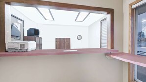 Een kamer met dakraam, houten deur, klok en televisie op een standaard.
