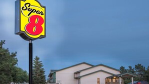 Een Super 8 motel met een parkeerplaats, een overdekte parkeerzone en een gebouw met een groen dak.