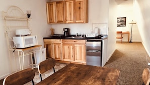 A compact kitchen with wooden cabinets, a microwave, a coffee maker, and a refrigerator. - Atlantic Breeze Inn (Old Orchard Beach)