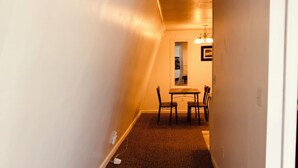 A narrow hallway with carpeted flooring leading to a dining area with a table and chairs. - Atlantic Breeze Inn (Old Orchard Beach)