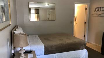 Ein Hotelzimmer mit einem Bett, einem Nachttisch mit Lampe, einem Spiegel und einer Tür.