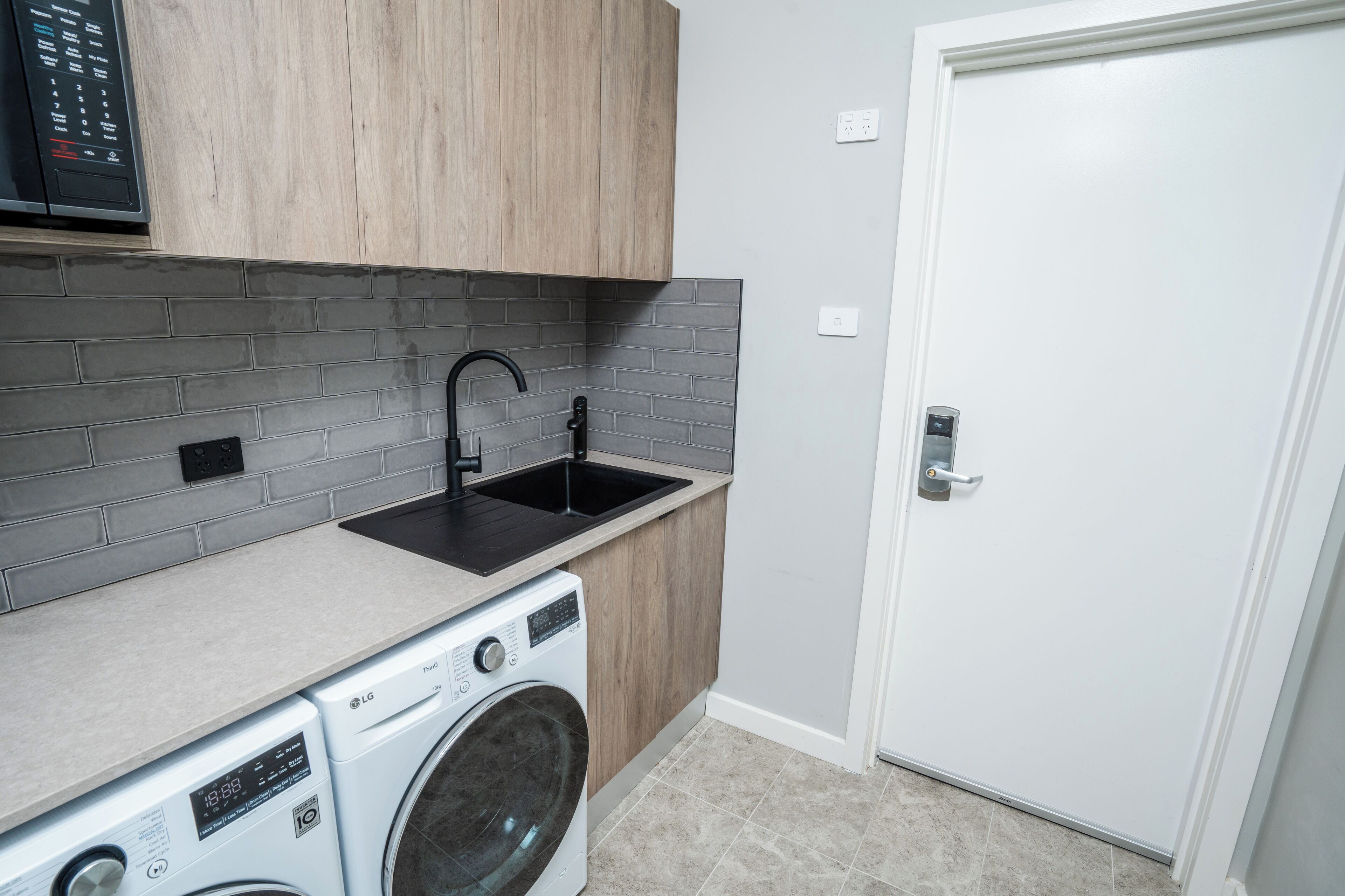 A compact kitchen with a washing machine, a sink, and a door.