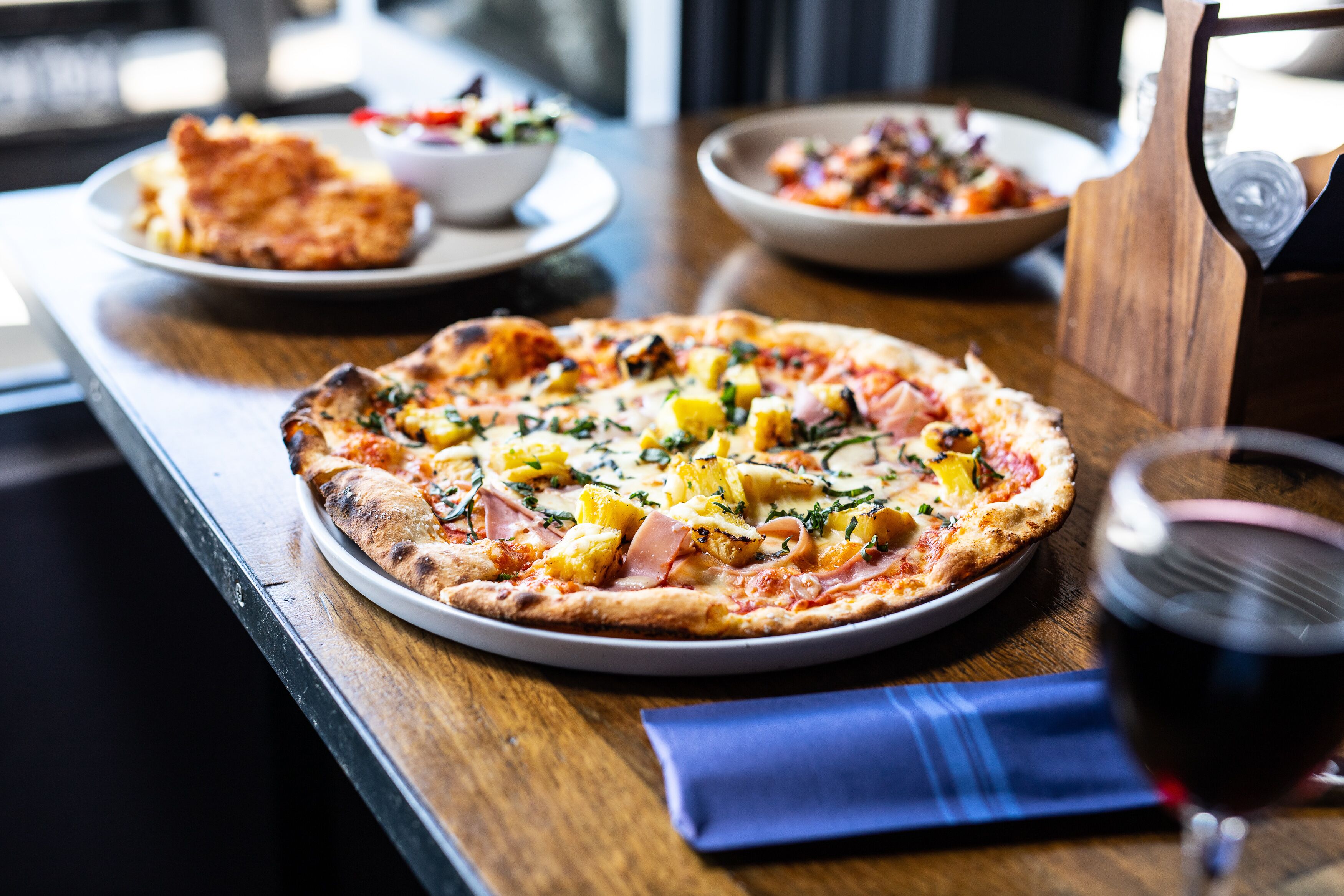 Una pizza con diferentes ingredientes sobre una mesa de madera.