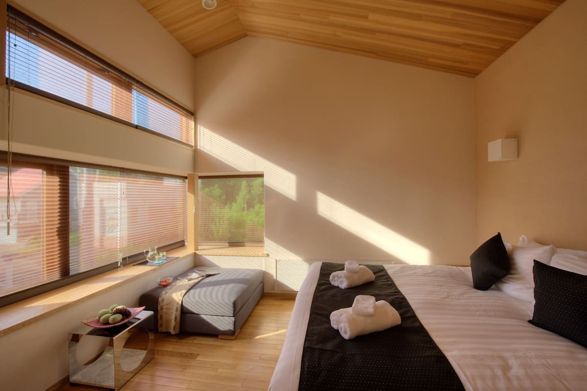 Un dormitorio moderno con una cama grande, una mesita de noche con un frutero y una ventana con persianas.