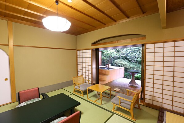 A traditional Japanese room with tatami flooring, a low table, and wooden chairs.