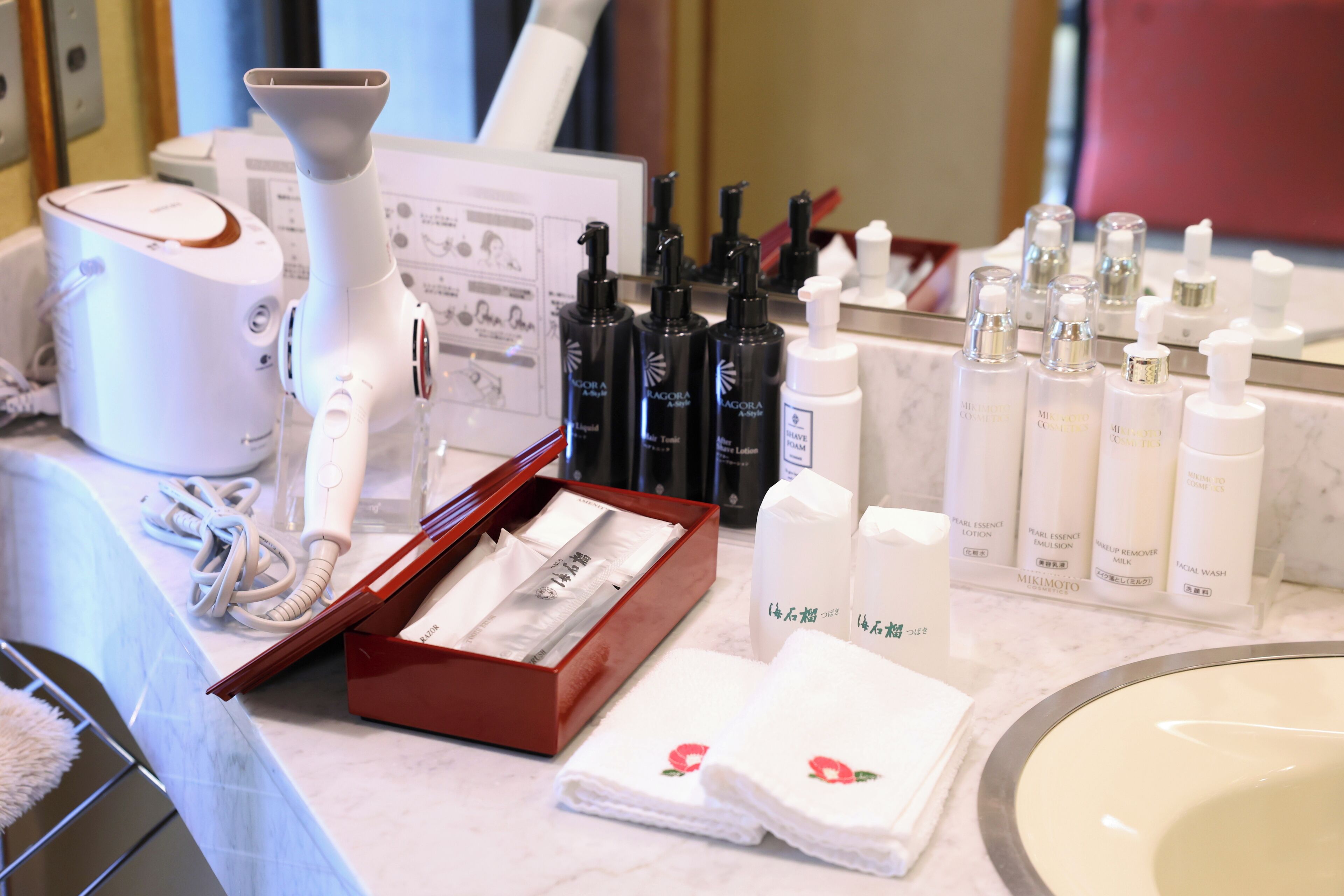 A bathroom vanity with a white sink, a mirror, and various skincare products.