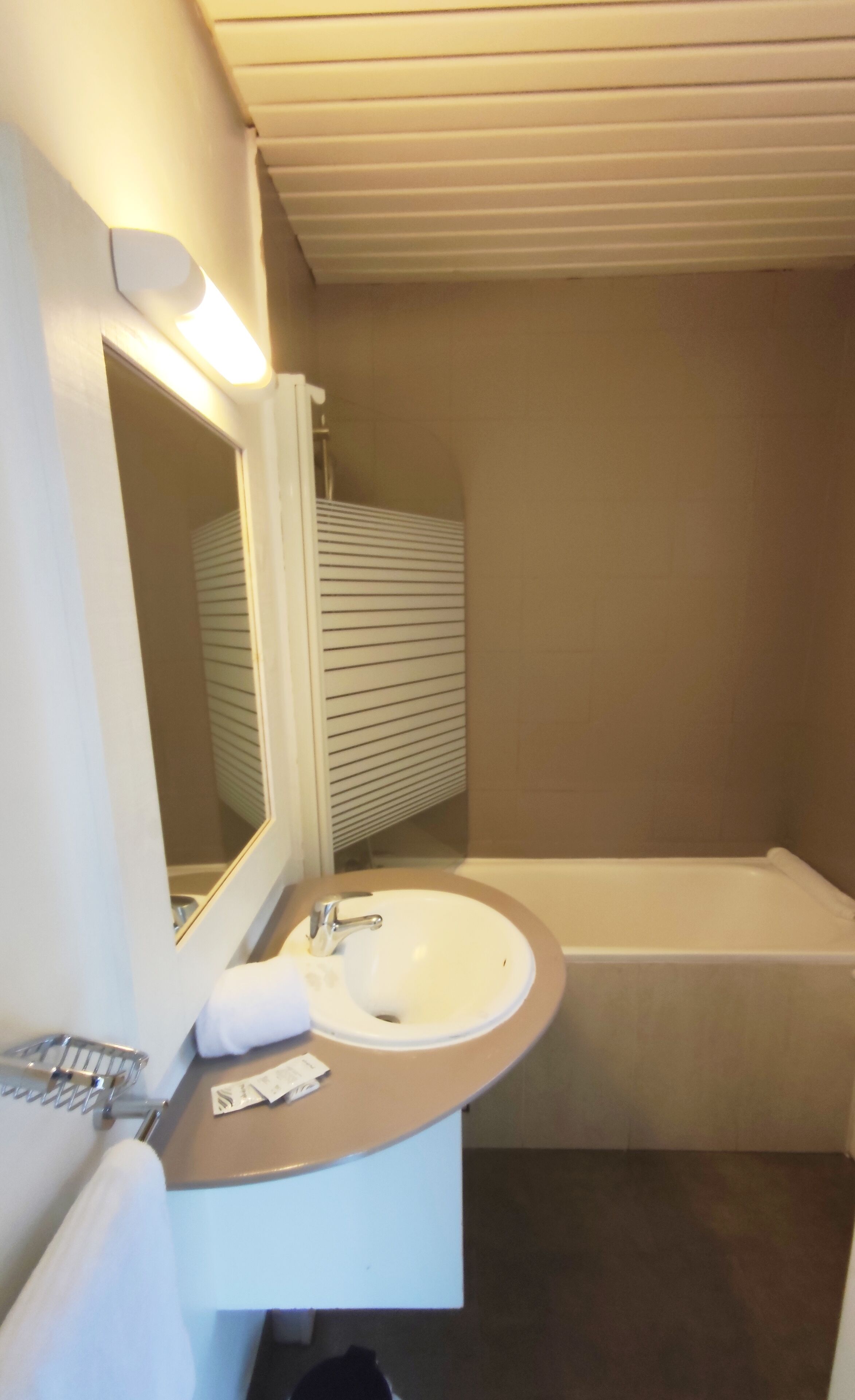 A bathroom with a sink, mirror, and bathtub.