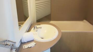 A bathroom with a sink, mirror, and bathtub.