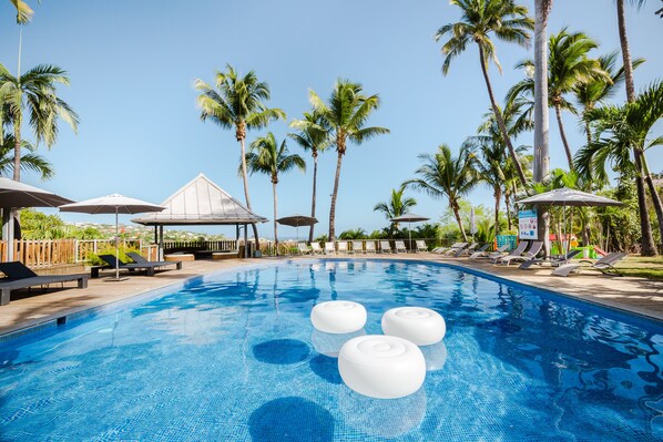 Una piscina al aire libre, sombrillas, sillones reclinables de piscina