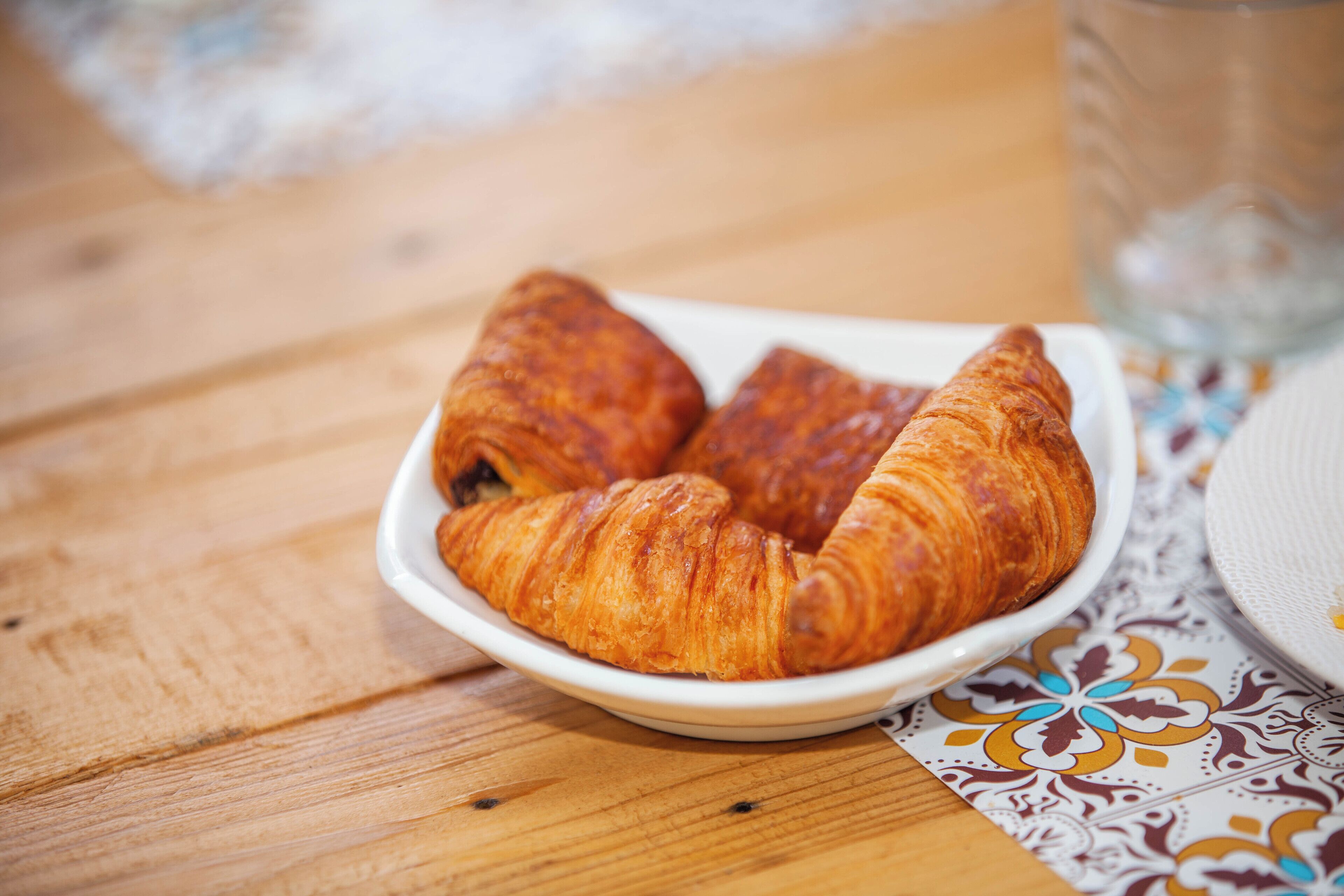 Una mesa de madera con un plato blanco que contiene croissants.