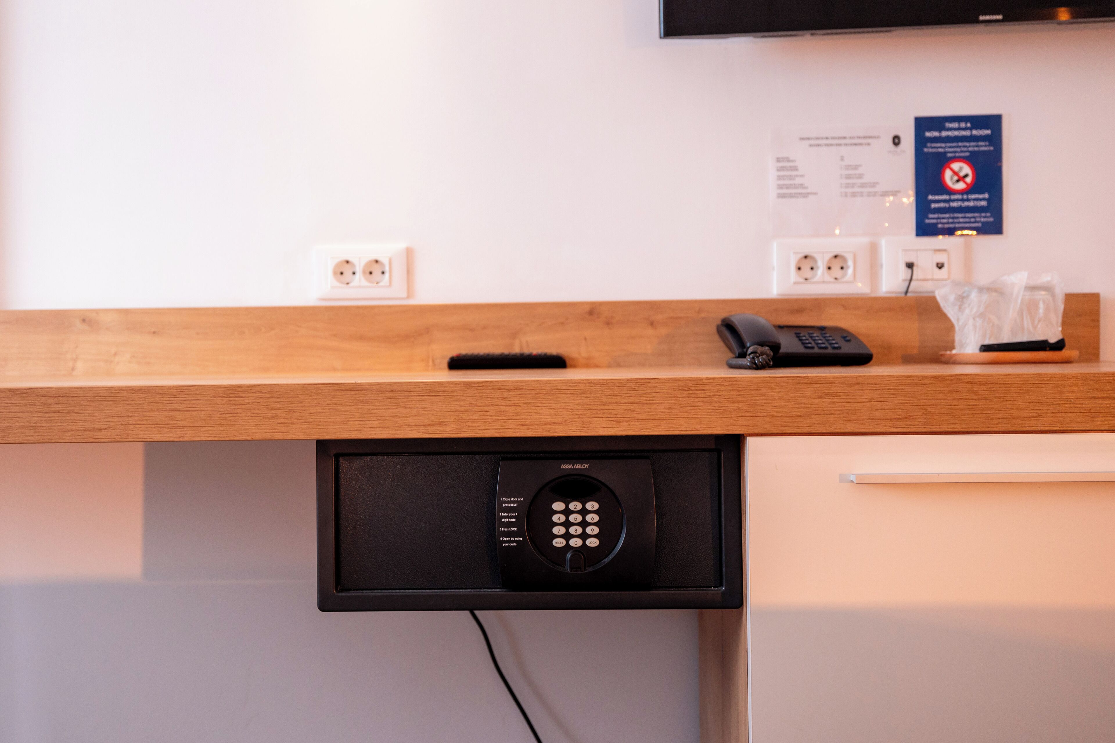 En hotellreception med en inbyggd telefon, en fjärrkontroll och ett digitalt knappsats.