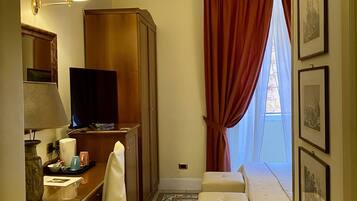 A hotel room with a desk, television, bed, and a view of the outdoors.