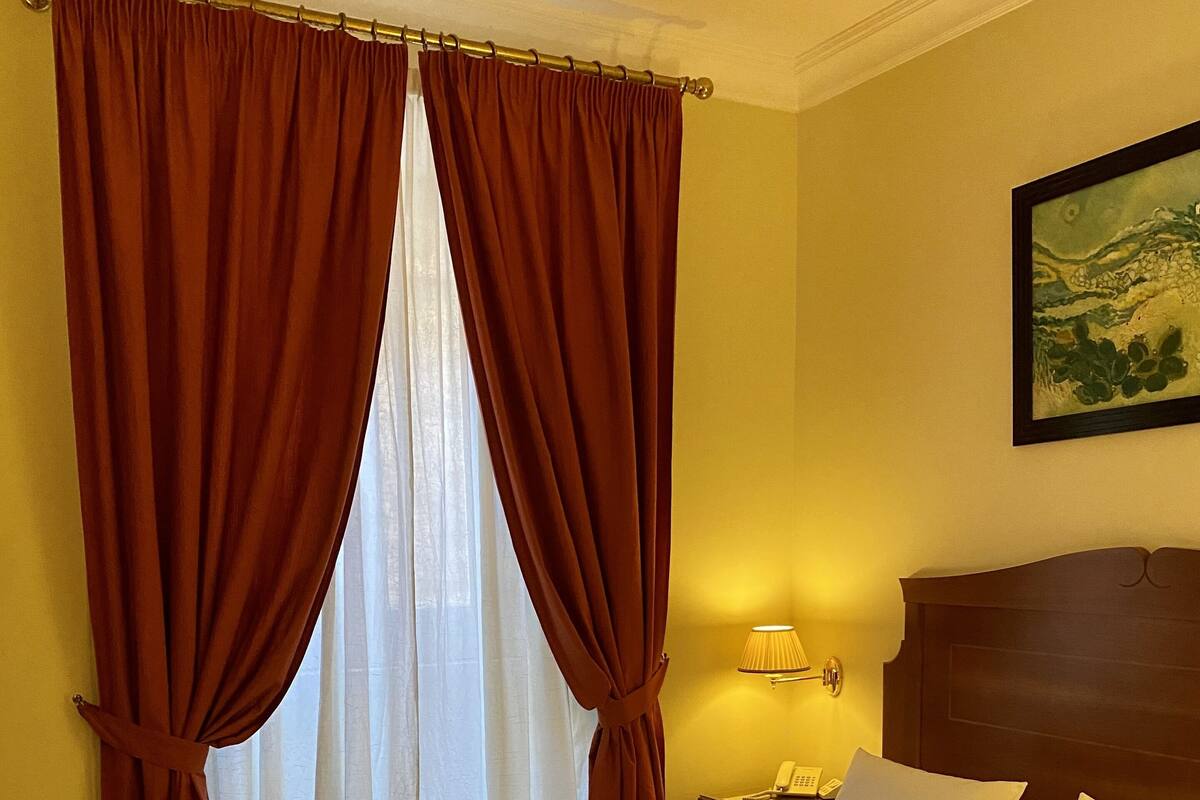 Una habitación de hotel con una cama grande, dos mesitas de noche, una lámpara y un cuadro en la pared.