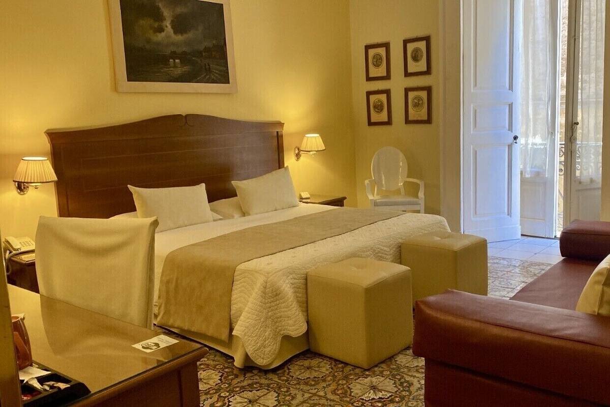 Habitación de hotel con cama, sofá, sillón y escritorio.