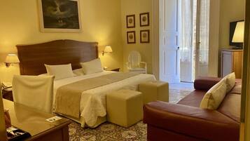 A hotel room with a bed, a sofa, a chair, and a desk.