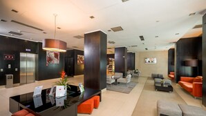 A modern lobby with a reception desk, seating area, and a television screen. - Hotel CH Bucharest (Bucharest)