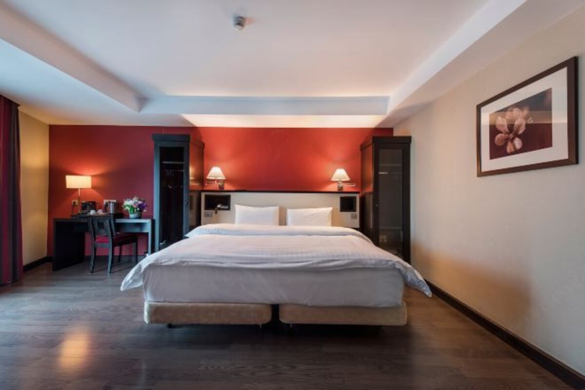 A hotel room with a double bed, bedside tables, a desk, and a chair.