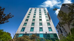 A modern high-rise building with the name "BUCHAREST" on the facade, surrounded by greenery. - Hotel CH Bucharest (Bucharest)