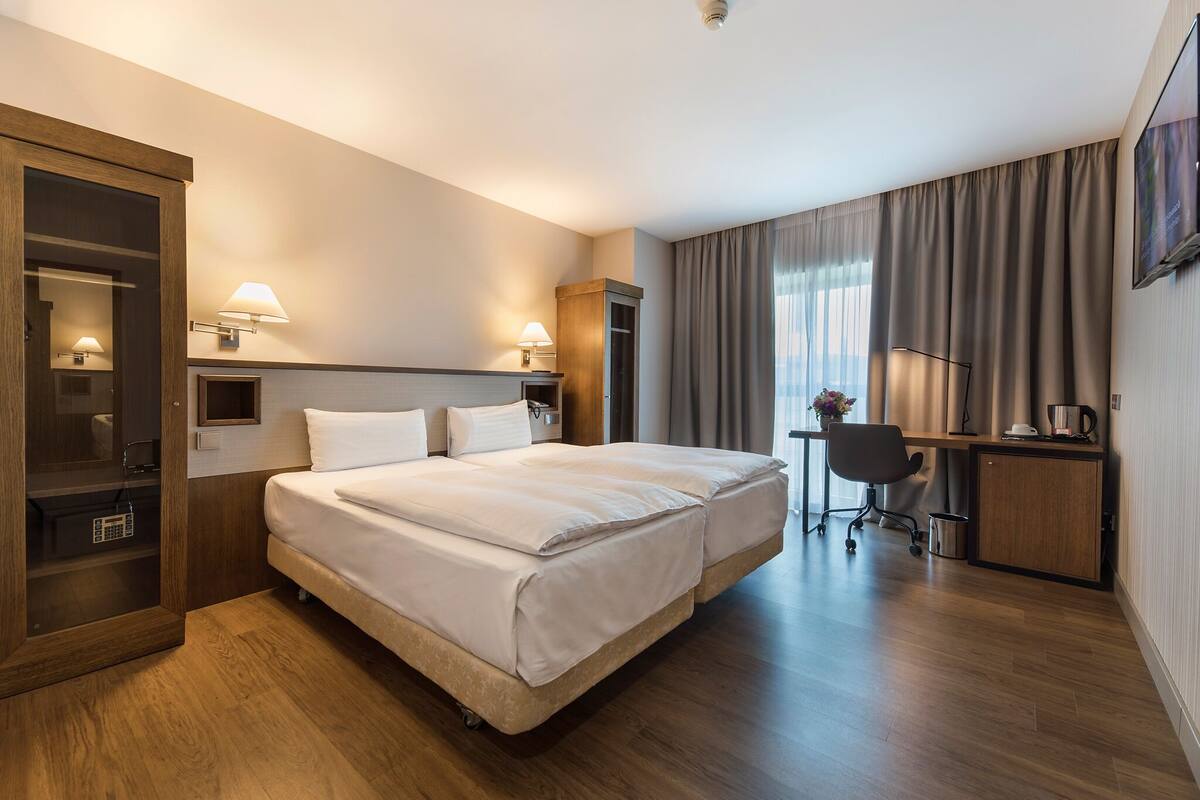 Una habitación de hotel con una cama grande, un escritorio, una silla y una televisión.