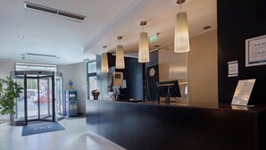 A hotel reception area with a revolving door, a reception desk, a clock, and a digital information board. - Hotel CH Bucharest (Bucharest)