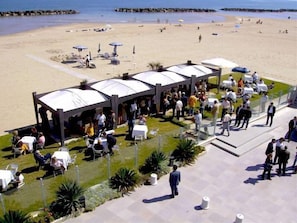 A beachside restaurant with outdoor seating and a covered patio area.