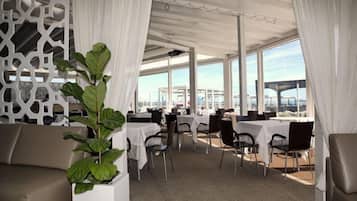 Un restaurante con cortinas blancas, mesas y sillas.