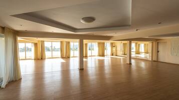 A spacious, high-ceilinged room with large windows and wooden flooring.