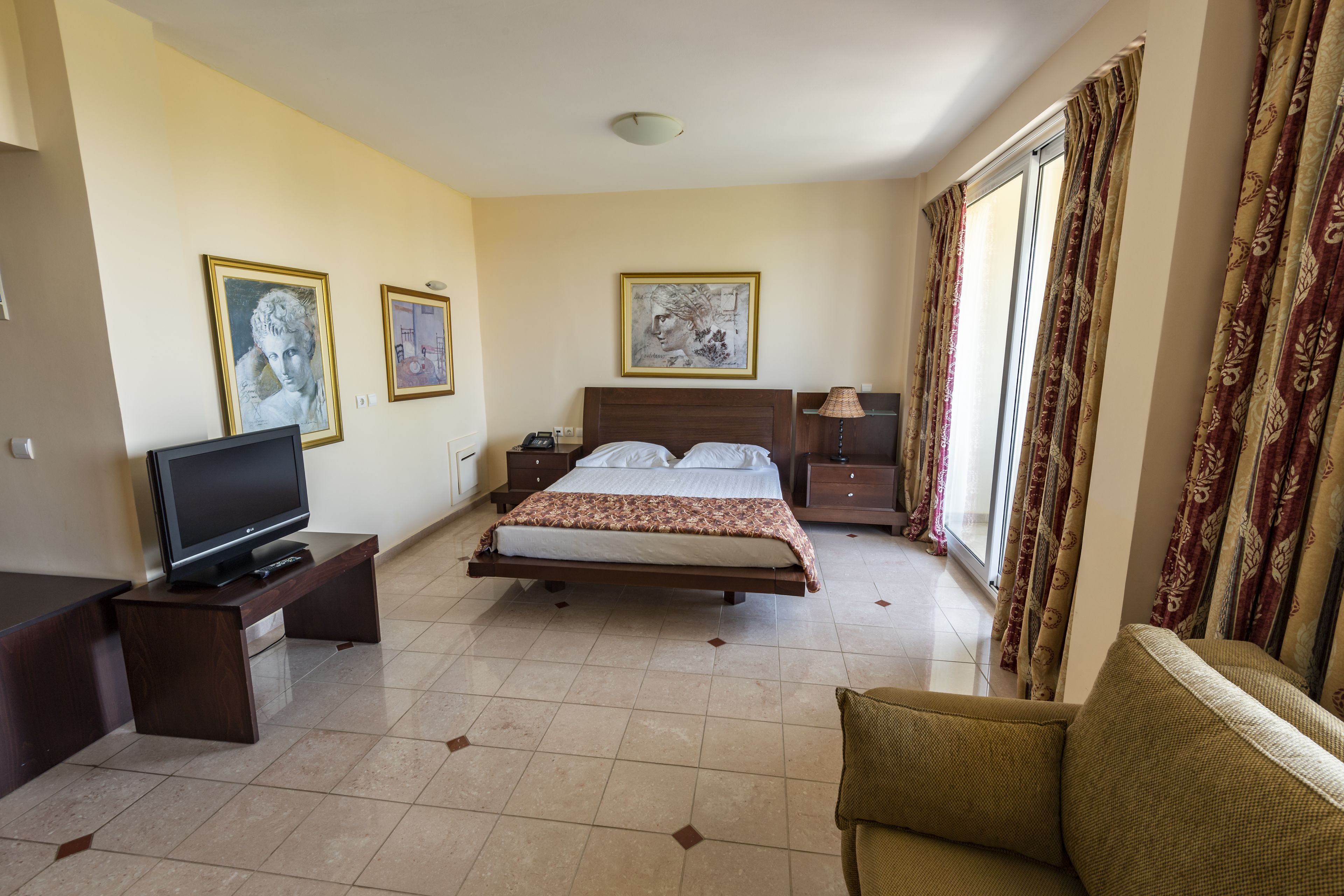 Una camera d'albergo con un letto, una televisione, una scrivania e un divano.